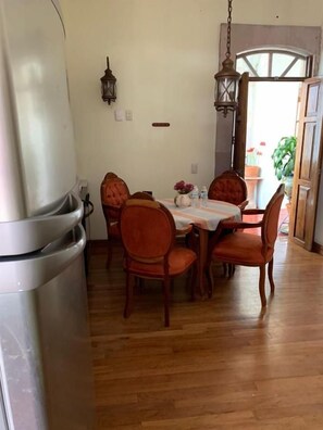 A dining area with a wooden table and chairs, a refrigerator, and a hanging light fixture. - Casa del Pingorongo (Zacatecas)