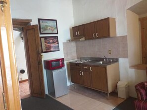 A compact kitchen with wooden cabinets, a microwave, and a small refrigerator. - Casa del Pingorongo (Zacatecas)
