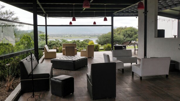 A modern outdoor lounge area with seating and a view of a lake and mountains. - Quinta del Lago (Querétaro)