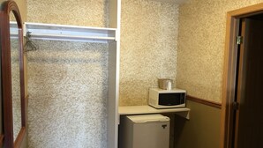 A compact utility room with a white refrigerator, a microwave on top, and a wooden door. - Budget Inn (Jefferson City)