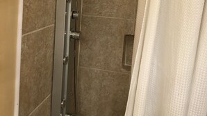 A shower with a handheld showerhead, a glass door, and a towel rack. - Budget Inn (Jefferson City)