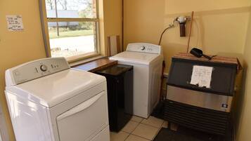 A laundry room with two washers and a dryer, a window, and a note on the dryer.