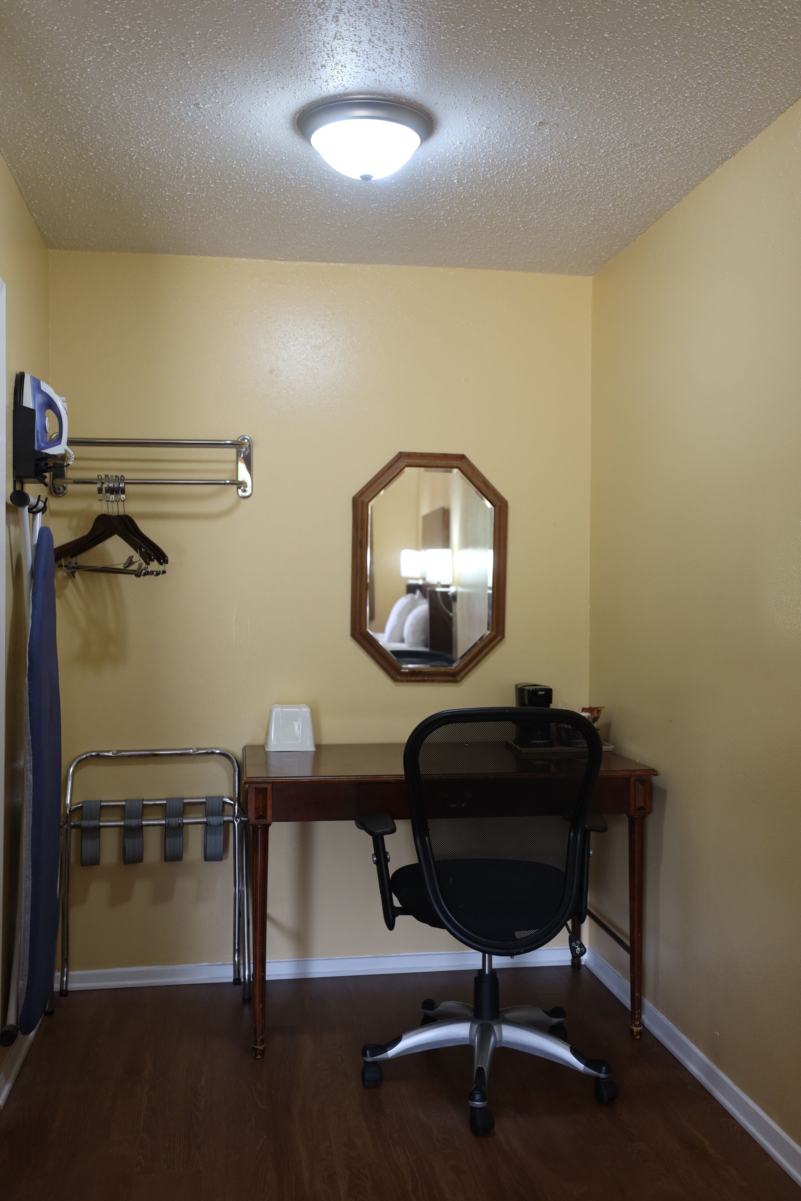 A small office with a desk, chair, and a mirror on the wall.