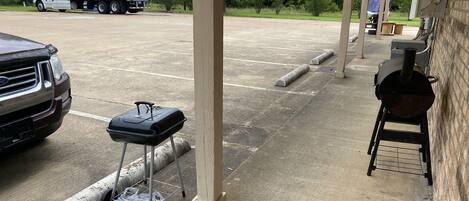 A covered outdoor area with a grill, a truck, and a covered seating area.