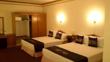 Habitación de hotel con dos camas, un armario, un escritorio y un espejo.
