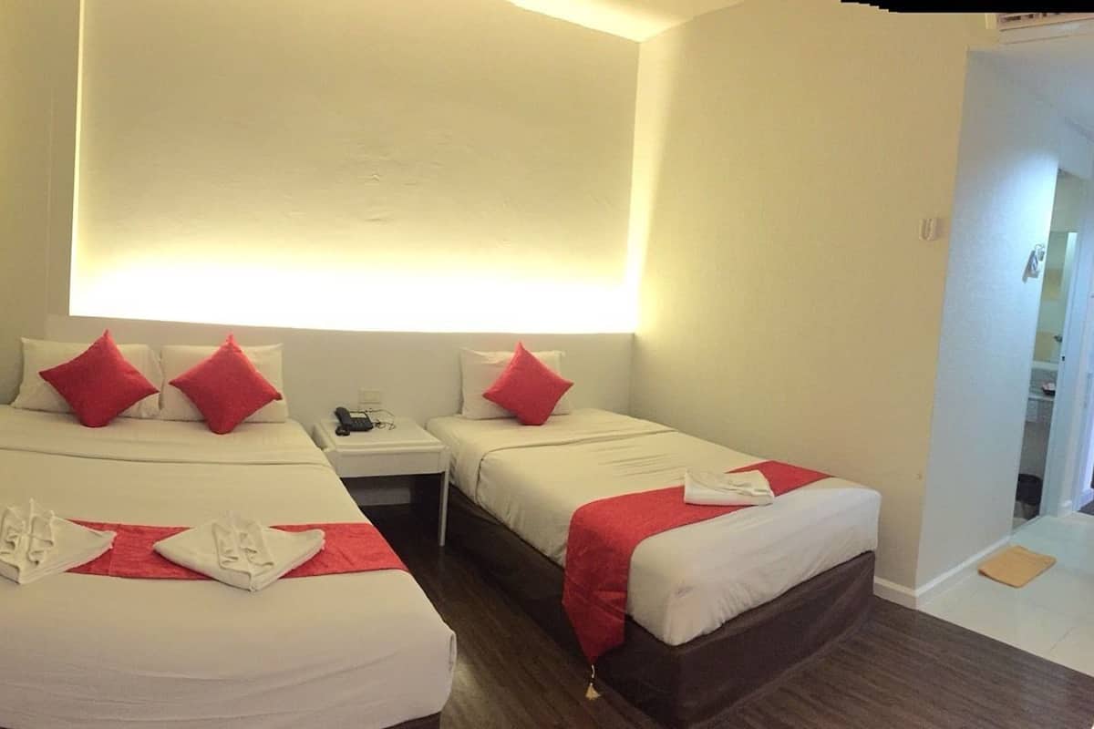Ein Hotelzimmer mit zwei Betten, jeweils mit roten Kissen und weißer Bettwäsche, einem kleinen Nachttisch und einem Stuhl.