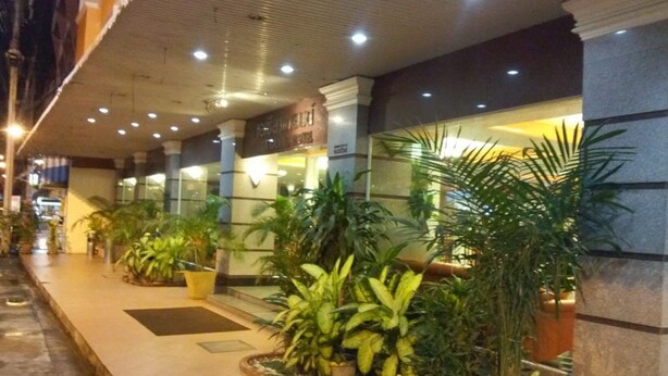 A hotel corridor with potted plants, a tiled floor, and a sign indicating a restaurant. - Asia Grand Hotel Hat Yai (Hat Yai)