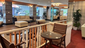 A modern hotel lobby with a seating area, a glass partition, and a view of the street outside. - Asia Grand Hotel Hat Yai (Hat Yai)