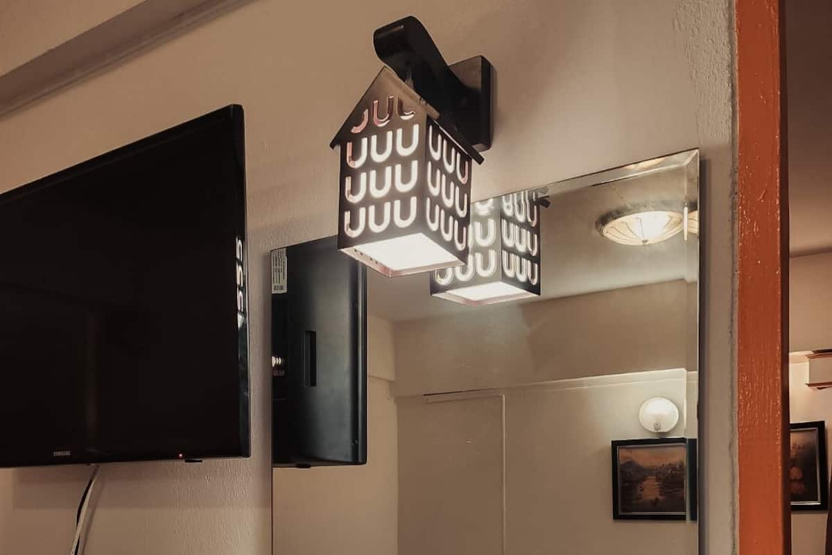 Ein Hotelzimmer mit Bett, Nachttisch und einem an der Wand befestigten Fernseher.