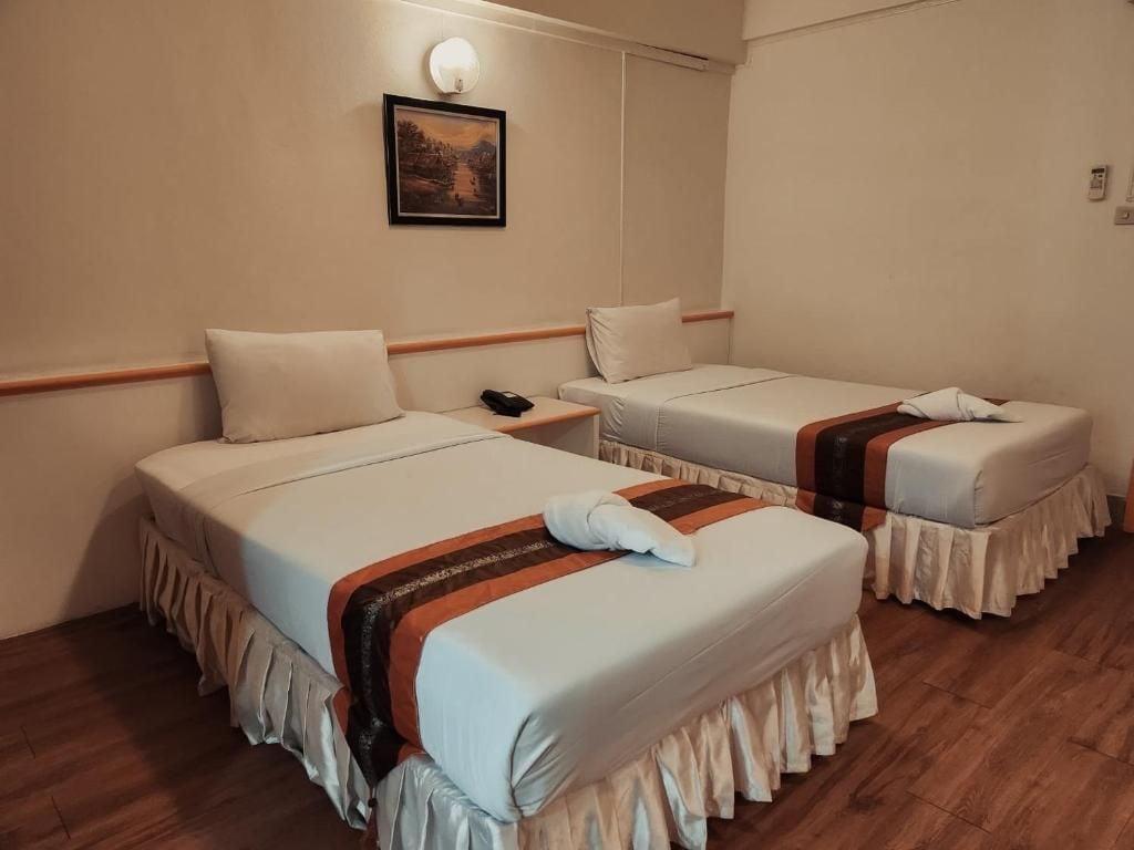 Habitación de hotel con dos camas, una mesita de noche con teléfono y una lámpara fijada a la pared.