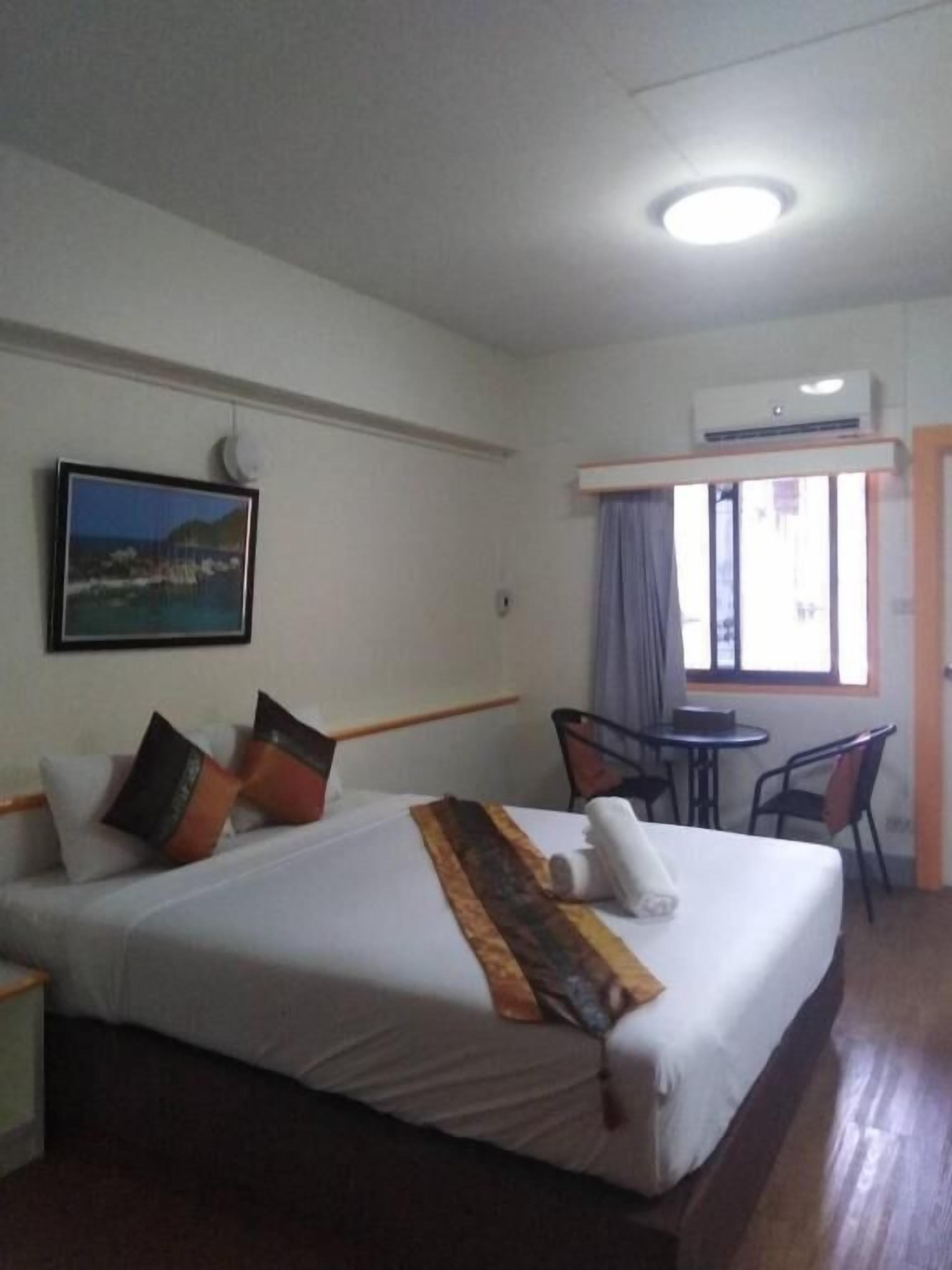 Une chambre d’hôtel avec un lit, un bureau, une chaise, une fenêtre avec des rideaux et un tableau au mur.