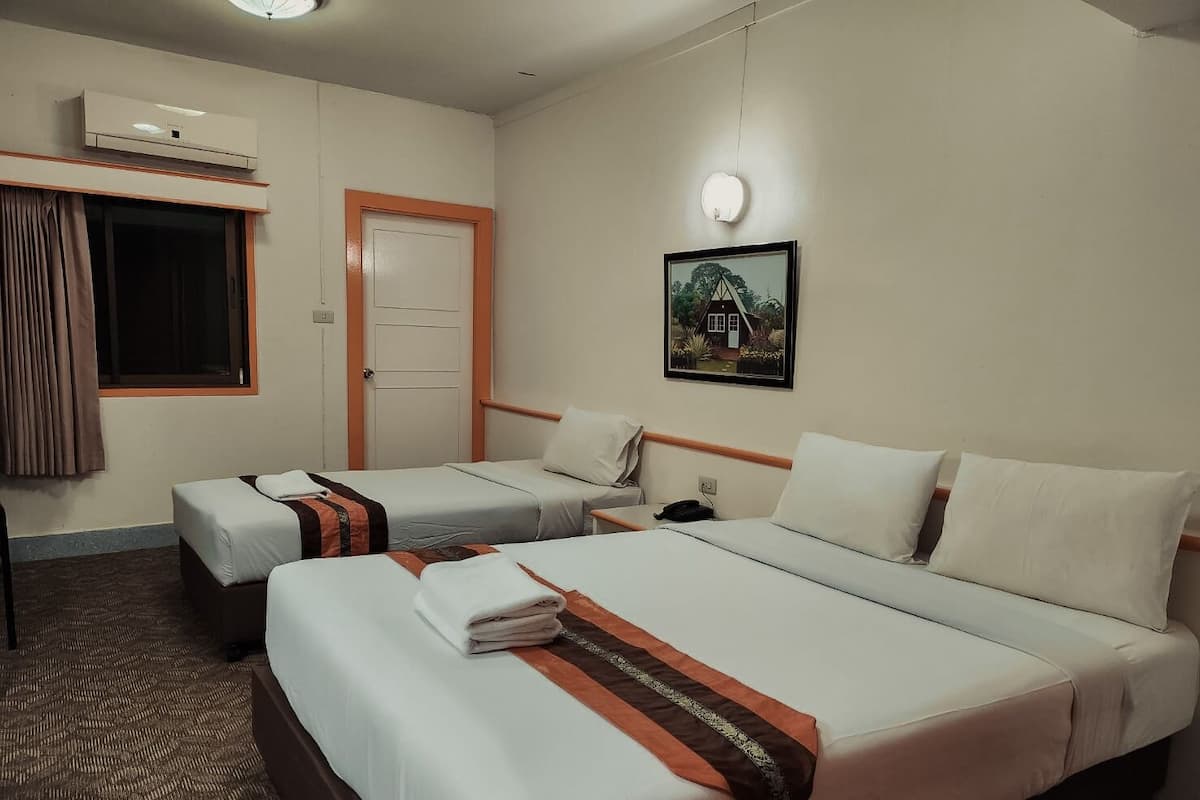 Ein Hotelzimmer mit zwei Betten, einem Fenster mit Vorhängen, einer Klimaanlage, einem gerahmten Bild an der Wand und einem Nachttisch mit Lampe.