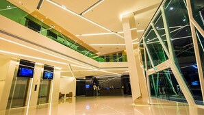 Een modern interieur met een glazen gevel, meerdere verdiepingen en een open centrale ruimte.