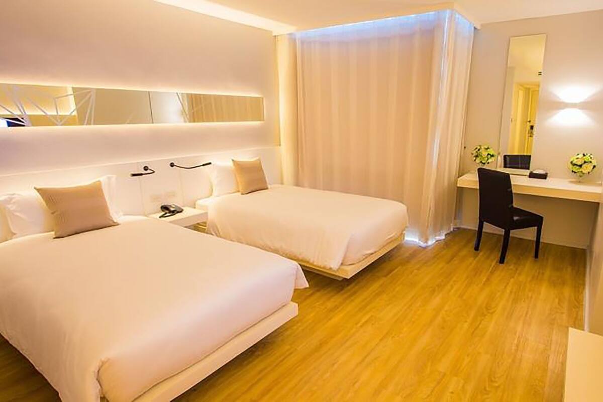 Een hotelkamer met twee bedden, een bureau, een stoel, een televisie en een grote spiegel.