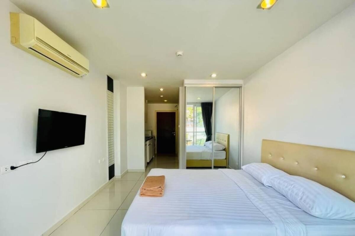 Une chambre d’hôtel équipée d’un lit, d’un téléviseur à écran plat fixé au mur et d’un appareil de climatisation.