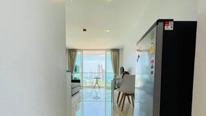 A modern hotel corridor with a large window, a dining area, and a refrigerator. - Art on The Hill by PSR ASIA (Pattaya)
