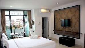 A hotel room with a large bed, a TV mounted on the wall, a small table with chairs, and a balcony with a view. - P'Residence (Hat Yai)