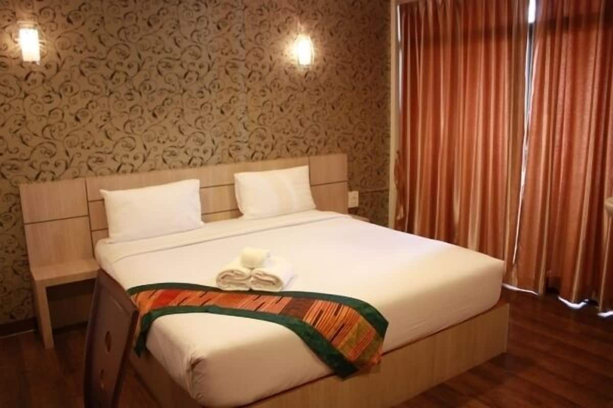 A neatly made bed with a striped bedspread and two pillows, a wooden headboard, and a patterned wallpaper.