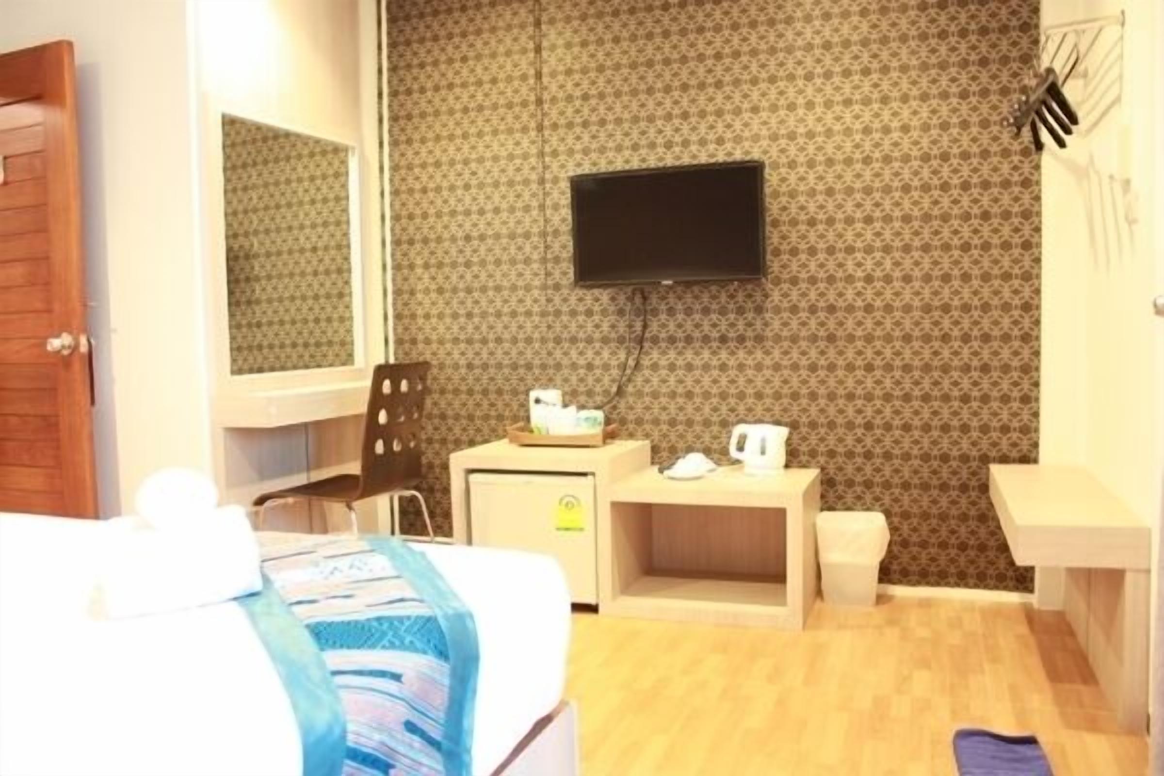 A hotel room with a bed, a desk, a television, a small cabinet, and a bathroom.