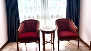 Een hoekappartement met twee rode fauteuils en een kleine ronde tafel.