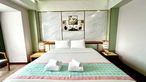 Een hotelkamer met een groot bed, twee nachtkastjes, een stoel en een wand met een decoratief paneel.