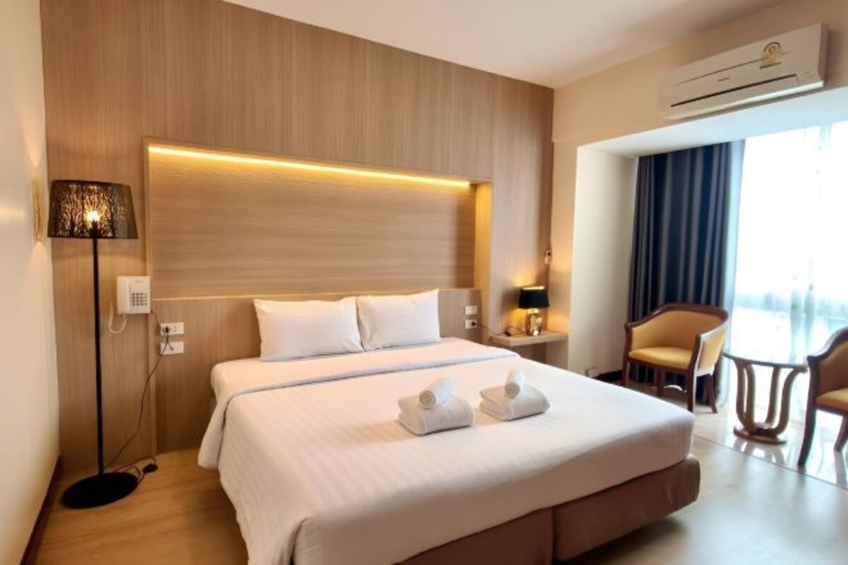 A hotel room with a large bed, bedside lamps, a desk, and a chair.
