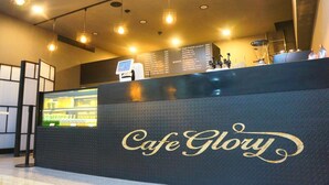 A reception area with a black counter displaying the name 'Cafe Glory' in gold lettering. There is a digital menu board above the counter listing various items and prices. - Gloryinn (Seoul)