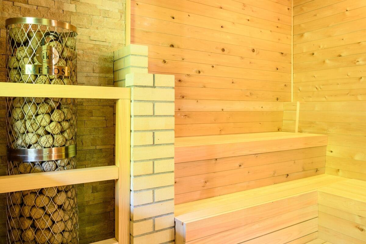 A sauna with wooden walls and a metal container holding logs.