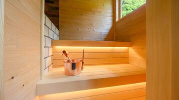 Una sauna de madera con un cubo de cobre y una cuchara para servir en un estante.