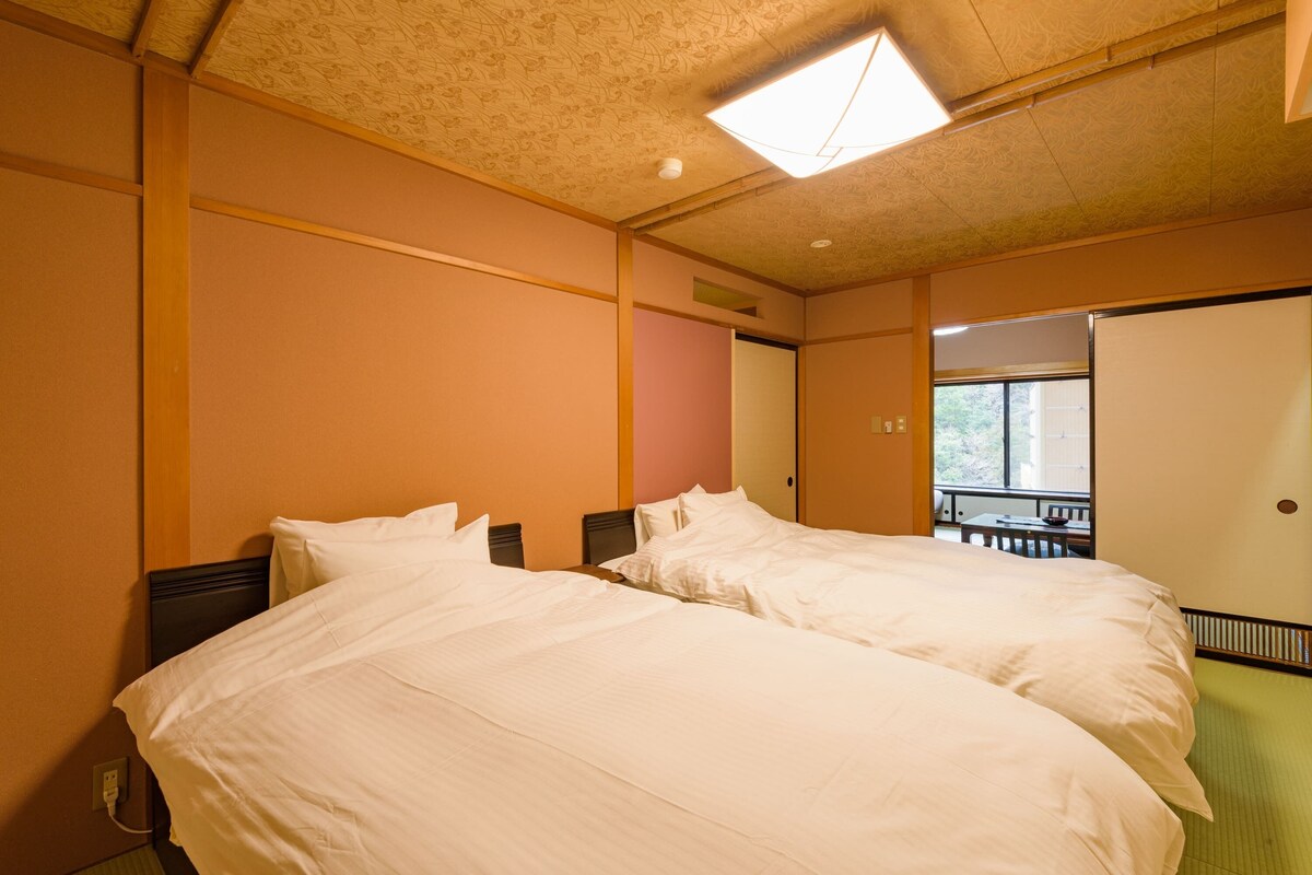 A hotel room with two beds, a window, and a door leading to a balcony.