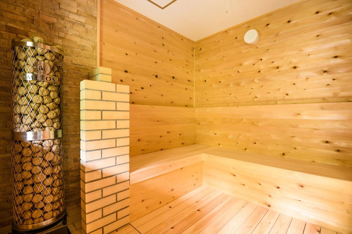 A sauna room with wooden walls and a brick structure.
