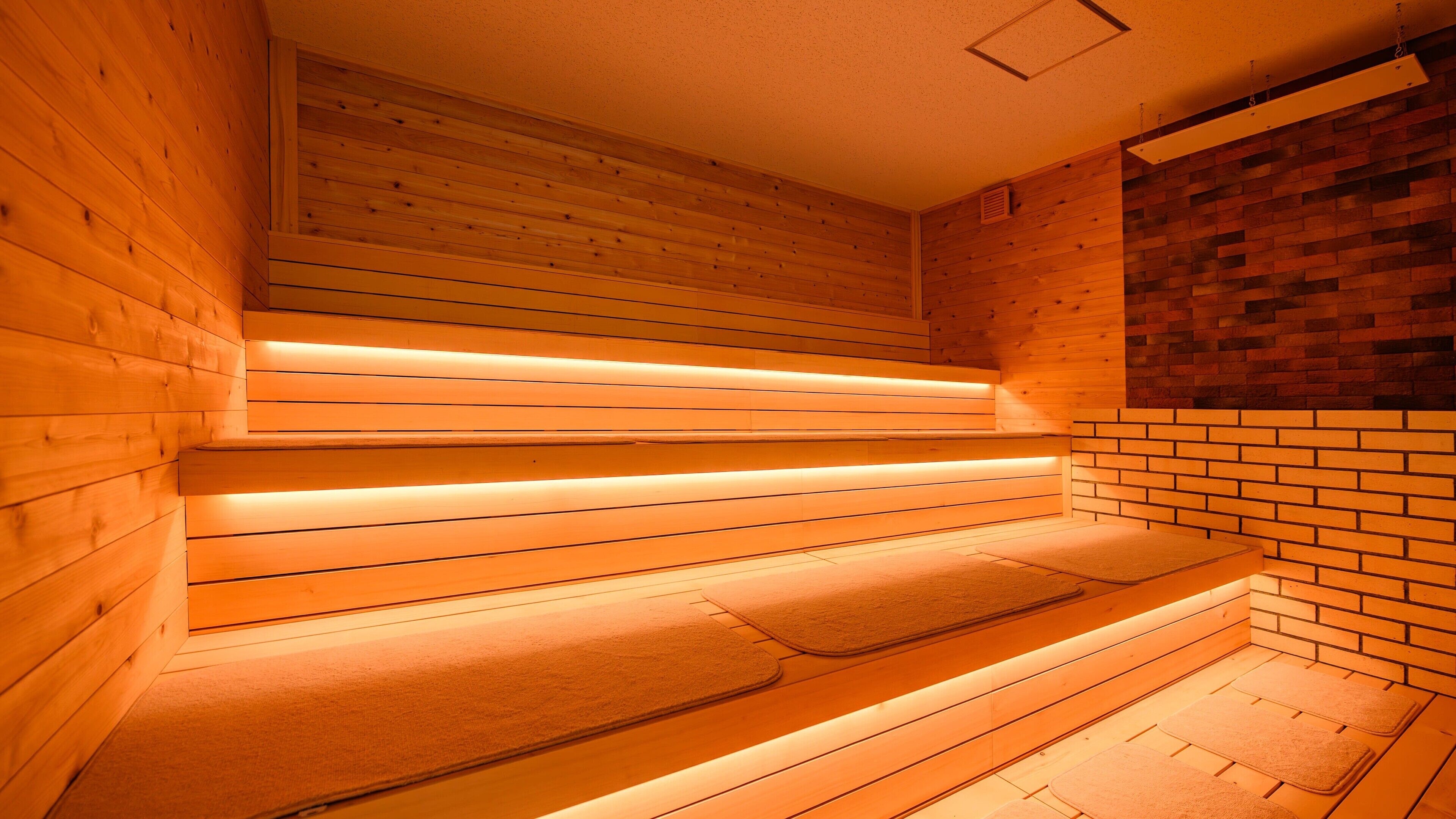A sauna with wooden benches and a brick wall.