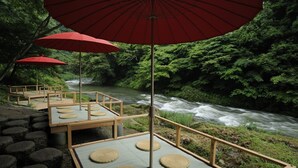 A riverside seating area with wooden platforms and red umbrellas.