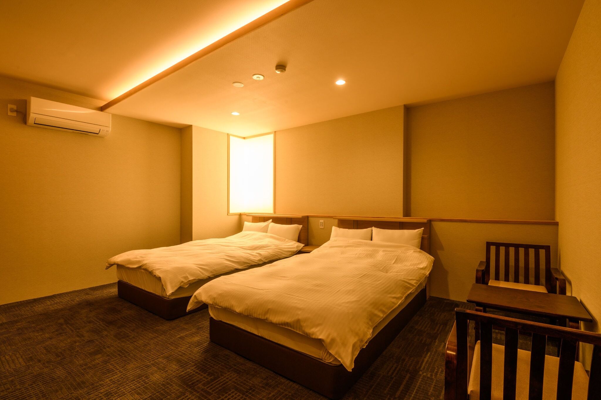 Una habitación de hotel con dos camas, una mesita y una silla.