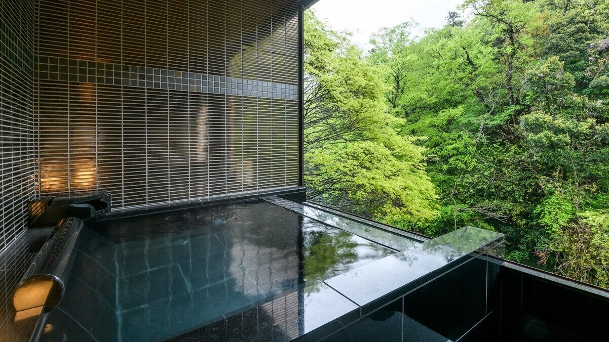 Ein modernes Interieur mit einem spiegelnden Boden, einer Sitzecke und Blick auf einen üppigen, grünen Wald.