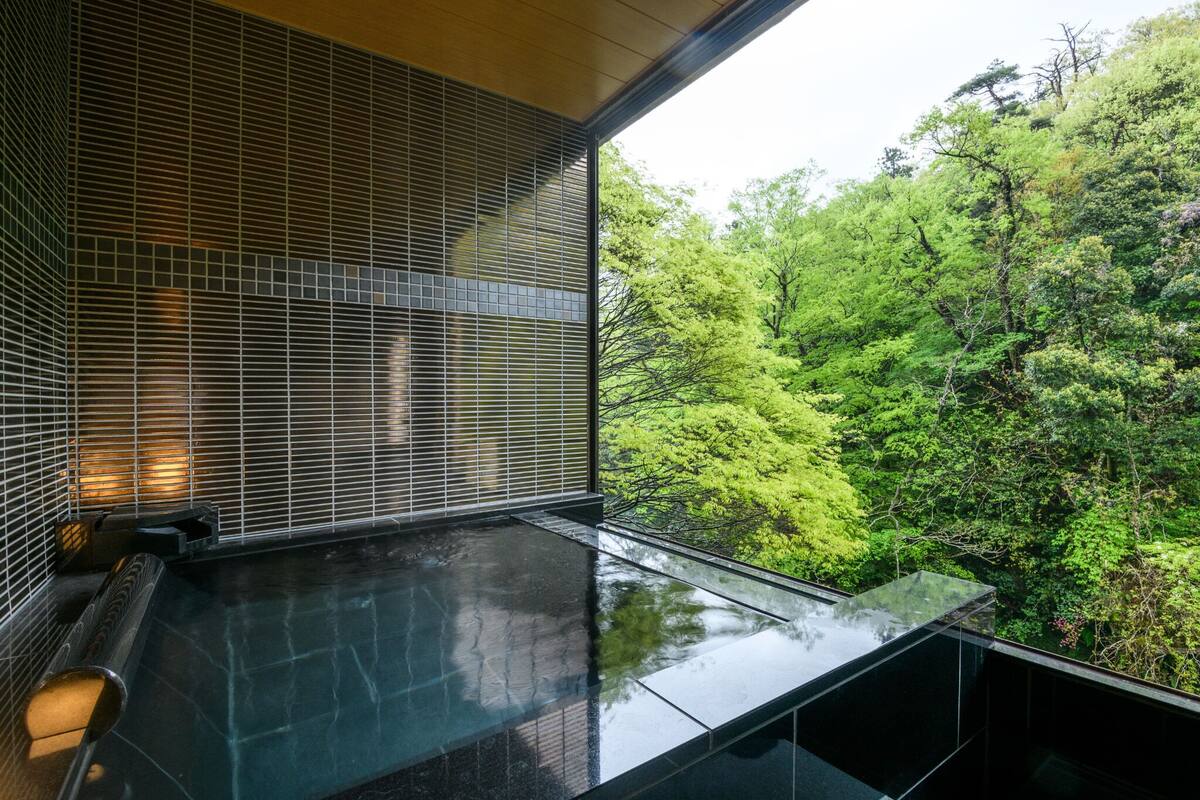 A modern interior with a glass balcony overlooking a lush forest.