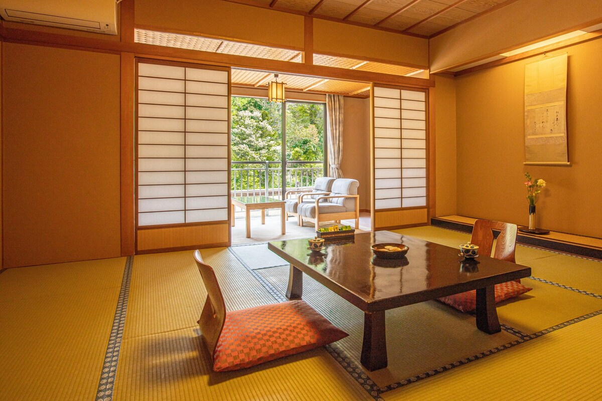 A traditional Japanese room with tatami flooring, a low table, and sliding doors.