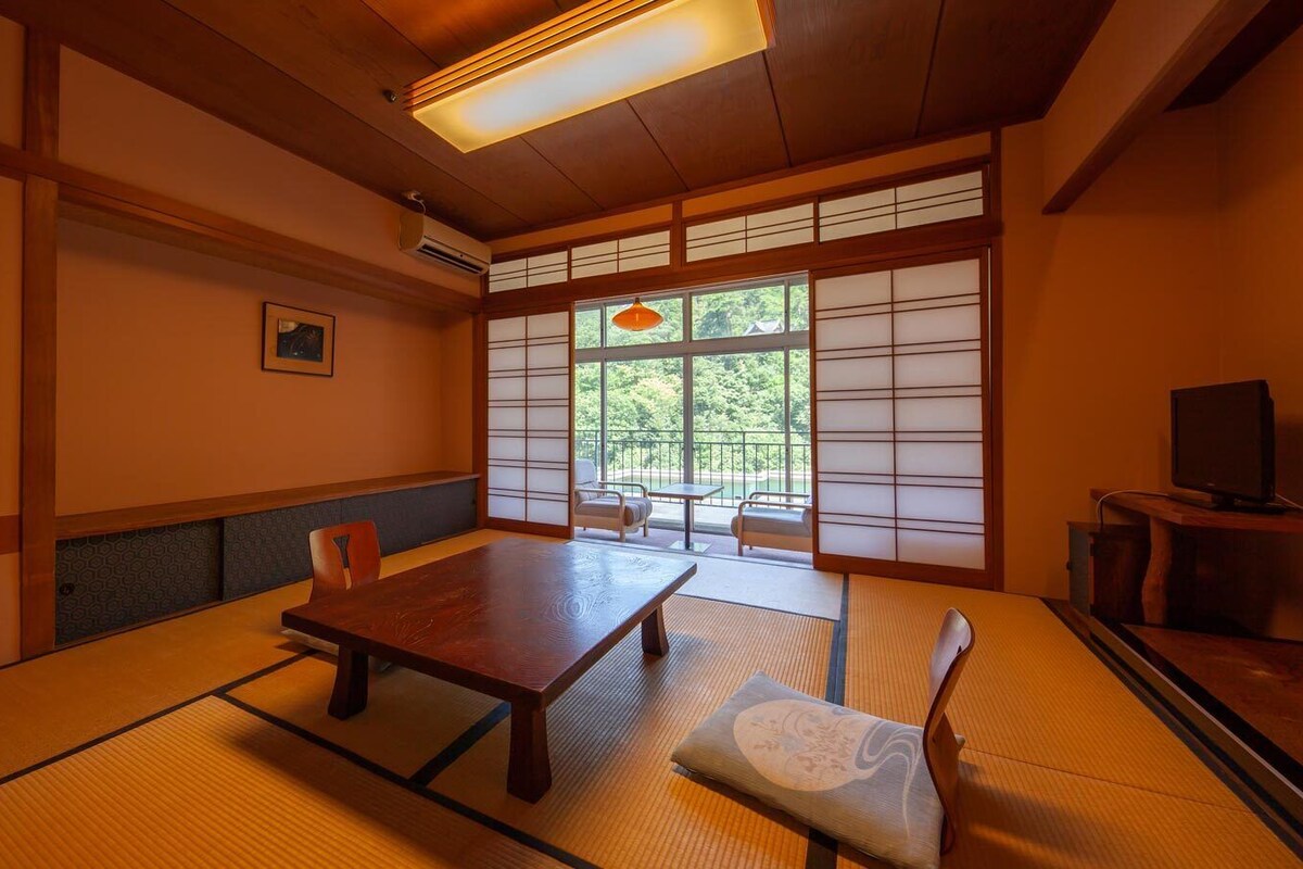 A traditional Japanese room with tatami flooring, a low table, and sliding doors.