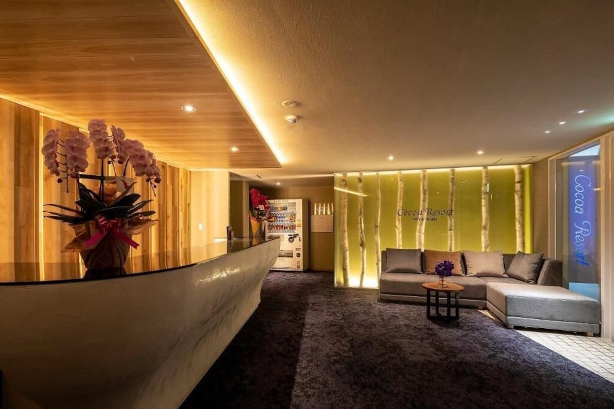 A reception area with a reception desk, a sofa, a small table, and a wall with a sign that reads 'Cocoa Resort.'