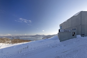 Un paisaje nevado con un edificio que dice "HOTEL Cocoa" y un cartel de estacionamiento.