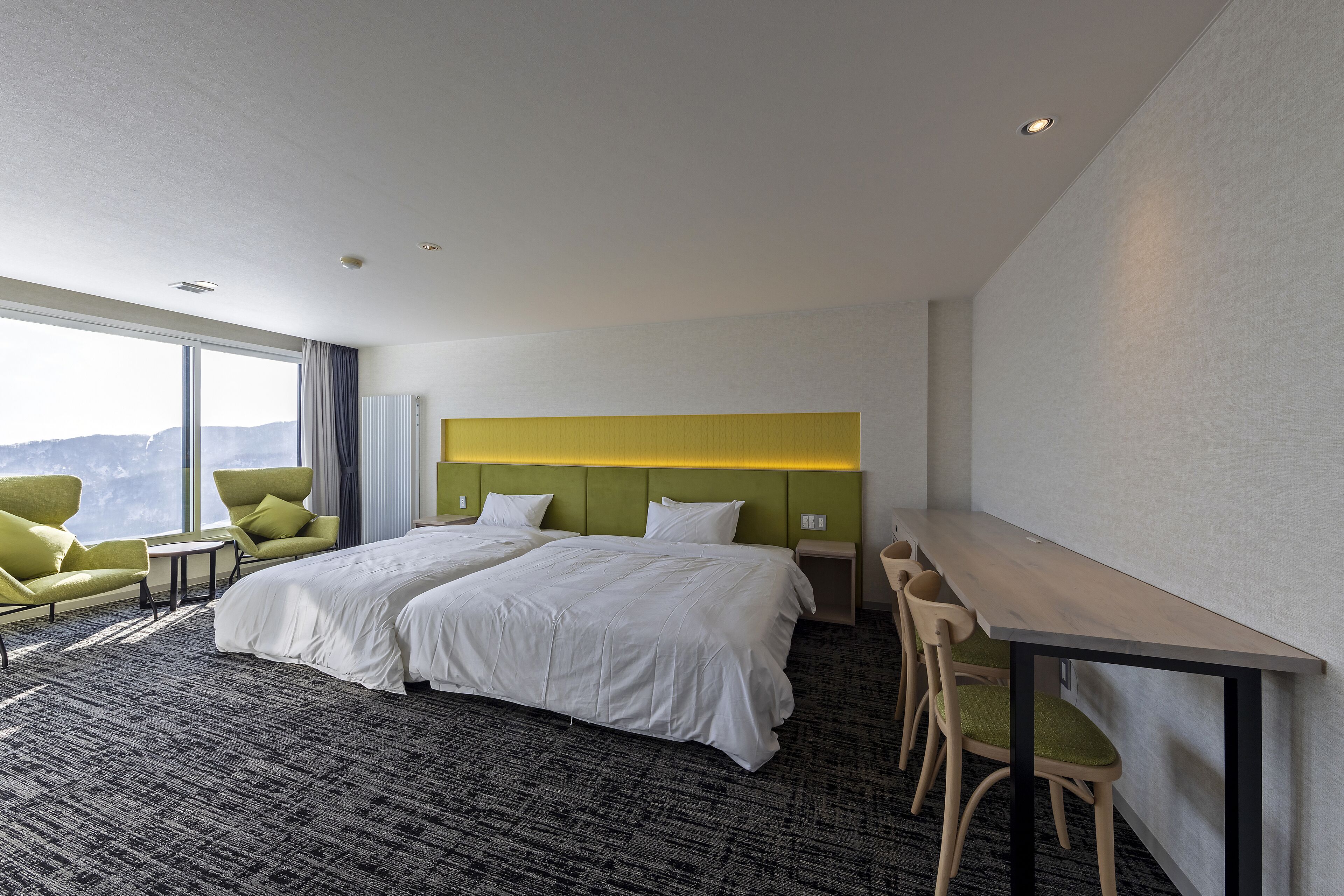 A hotel room with two beds, a desk, and chairs.