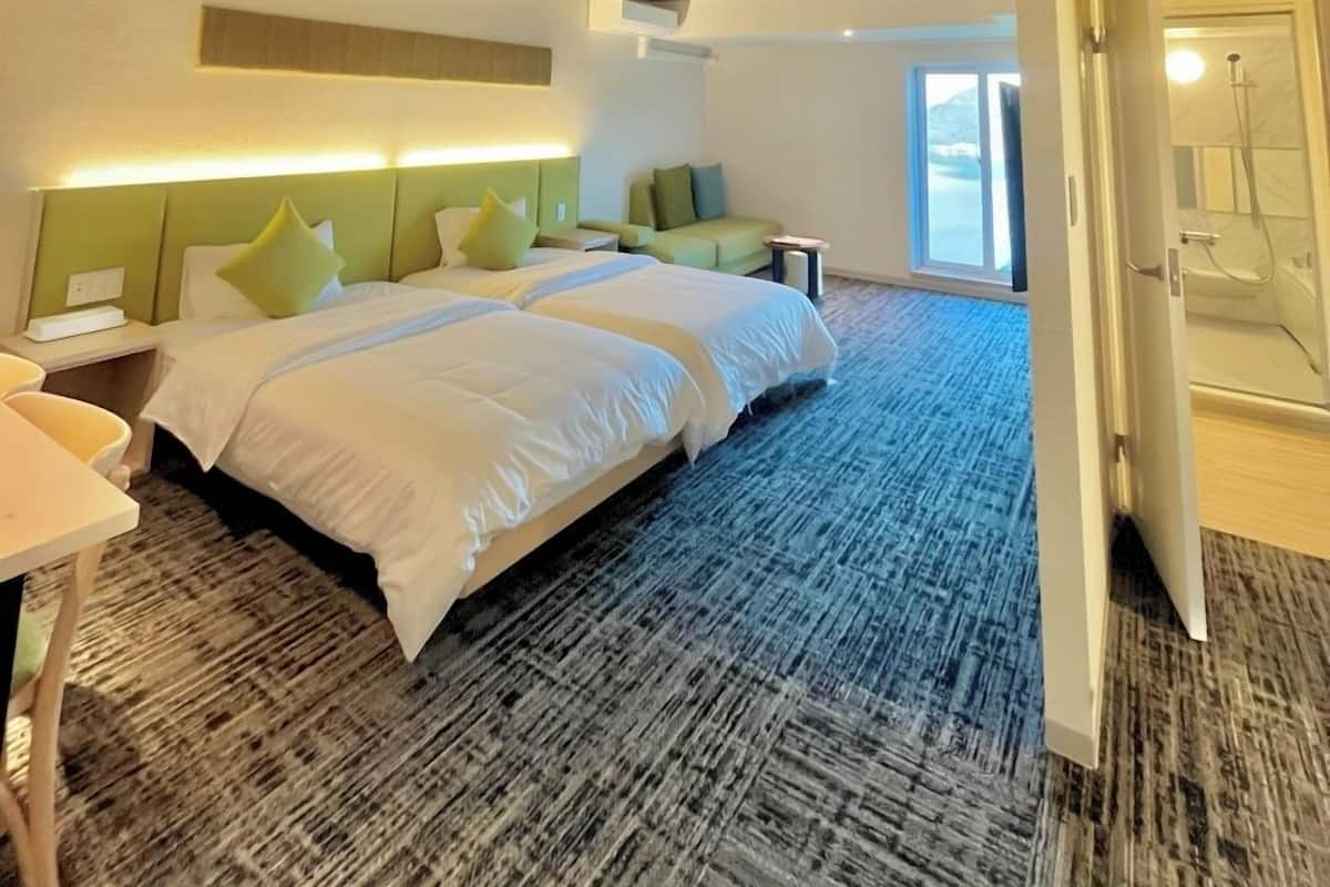A modern hotel room with a large bed, a desk, and a shower area.