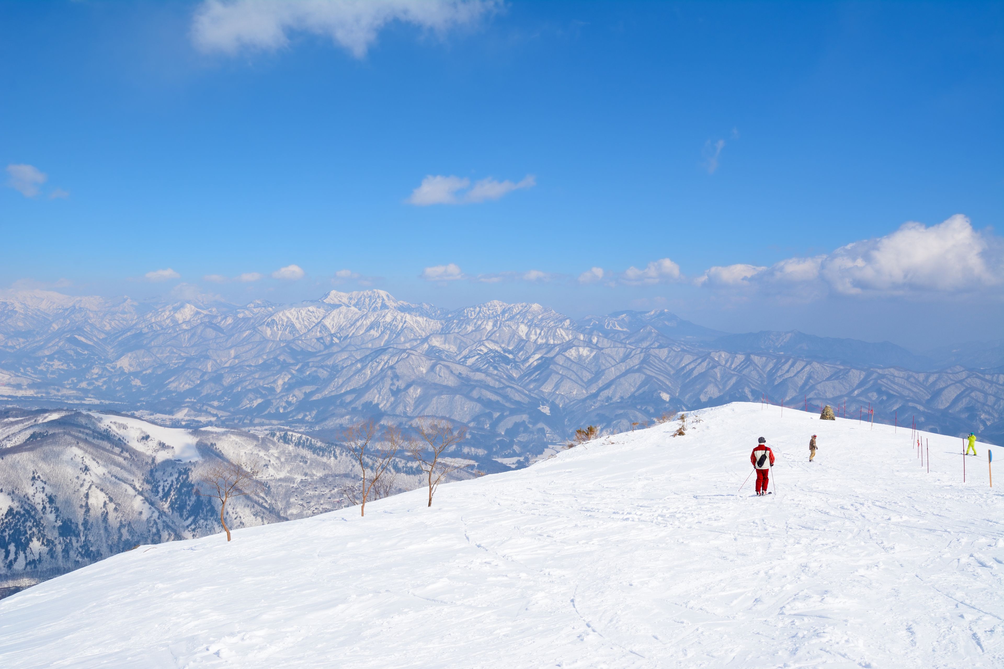 A snowy mountain landscape with skiers.