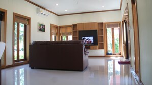 Amplia sala de estar con un televisor de pantalla plana grande, un sofá marrón y armarios de madera.