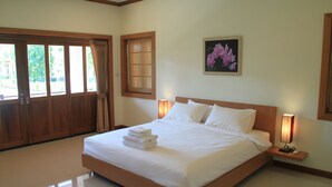 Habitación de hotel con una cama grande, una mesita de noche con lámpara, una ventana con cortinas y un cuadro en la pared.