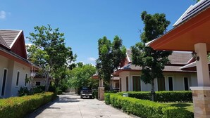 Una calle residencial con casas, una camioneta SUV estacionada y setos bien cuidados.