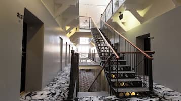A modern hotel interior with a central staircase, multiple floors, and a patterned carpet.