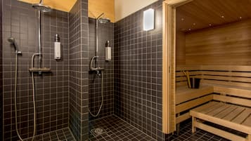 Uma sala de sauna com um banco de madeira, área de chuveiro com vários chuveiros e piso revestido de azulejos.