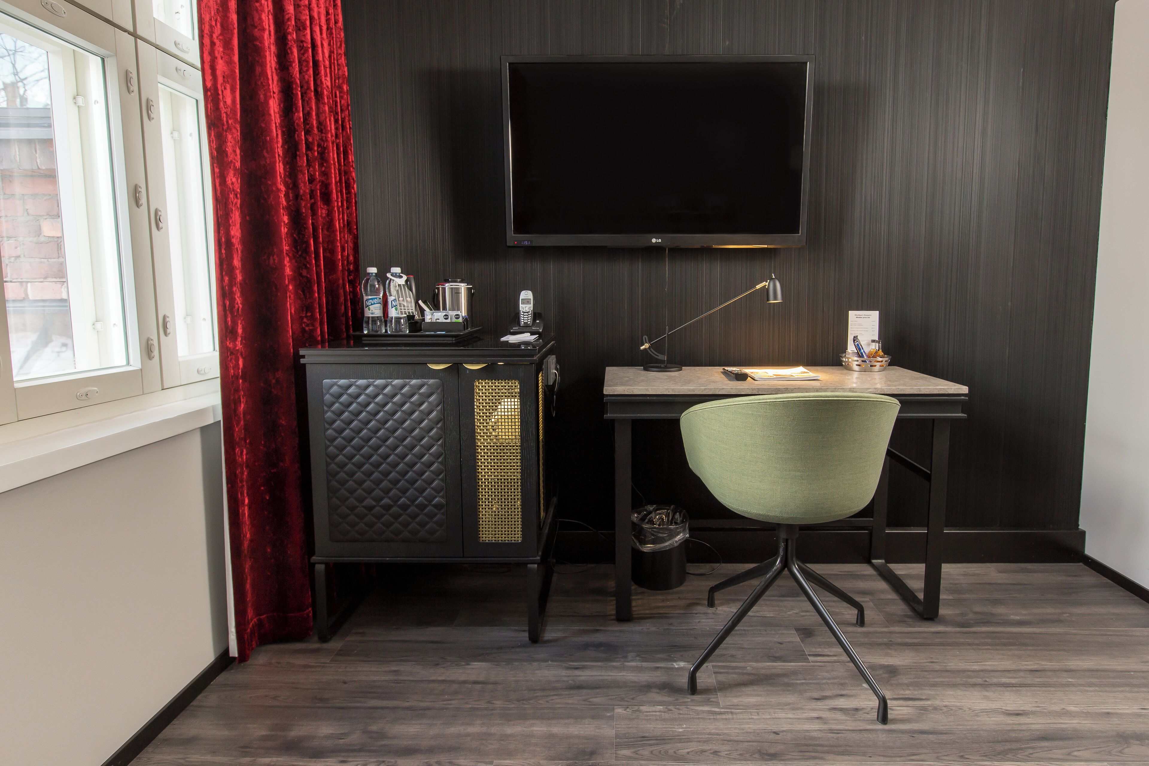 Un espace de bureau compact comprenant un bureau, une chaise et un téléviseur à écran plat fixé au mur.