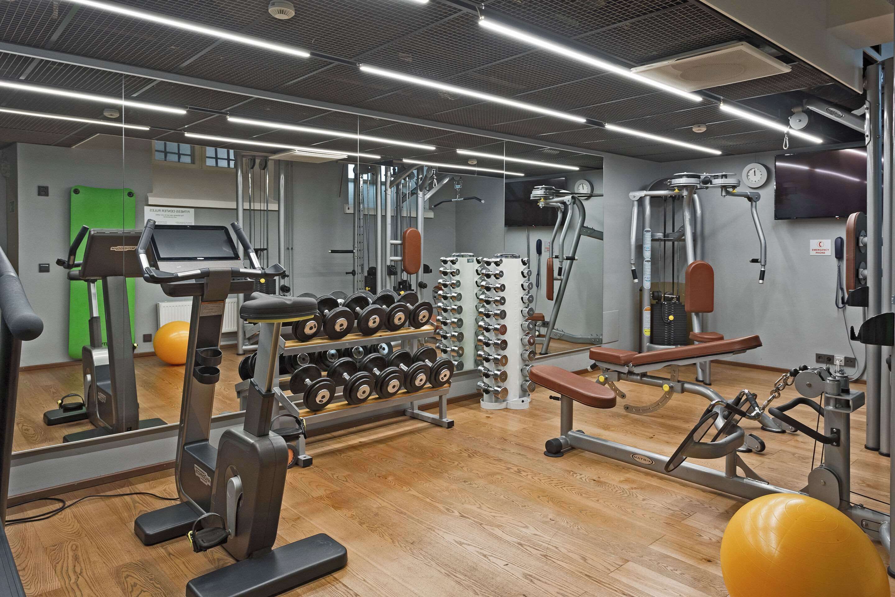 Un gimnasio con equipo de ejercicio, un espejo y una puerta verde.